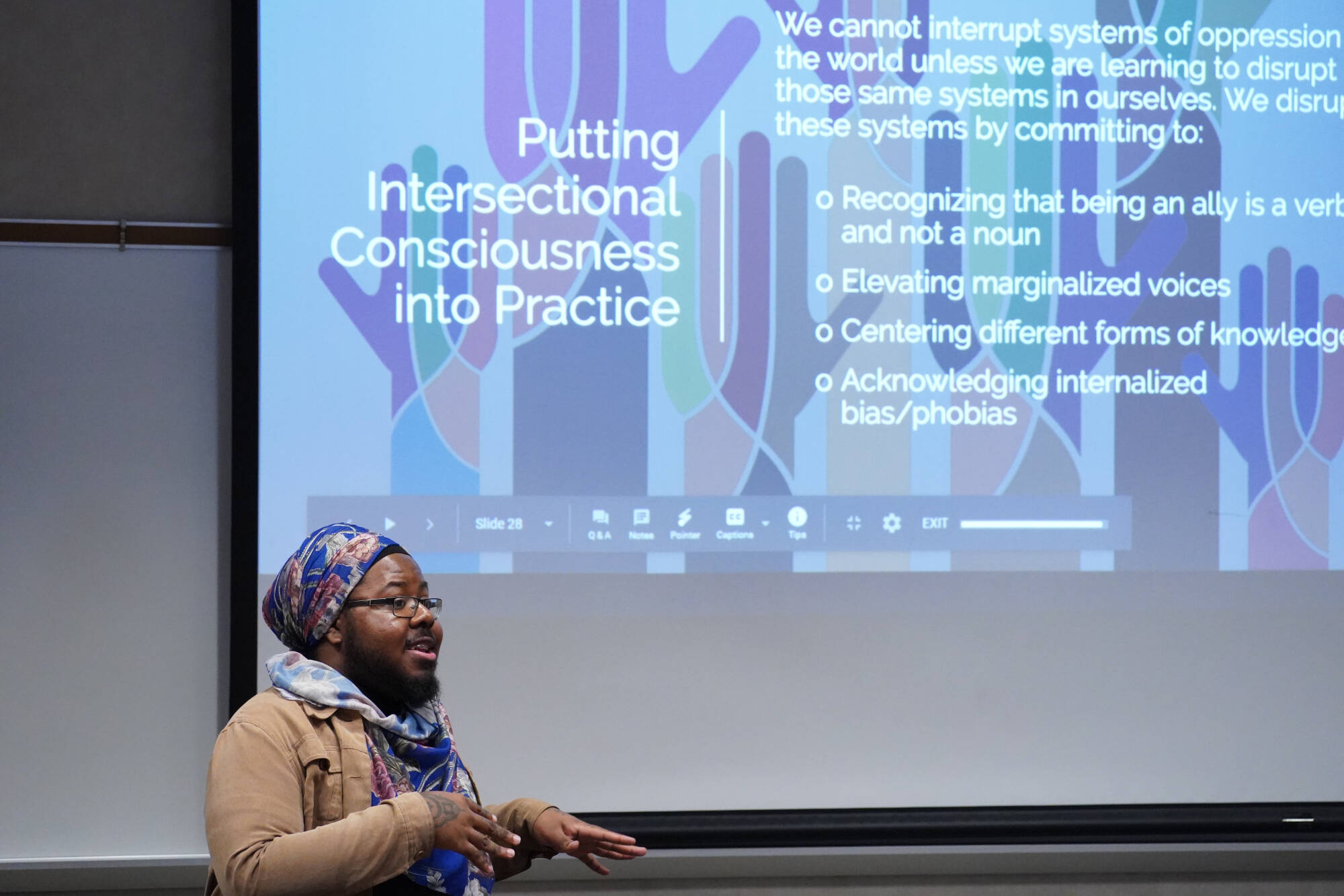 Speaker standing in front of a Putting Intersectional Consciousness into Practice slide